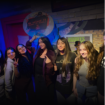 A group of girls pictured smilling while holding a we solved sign